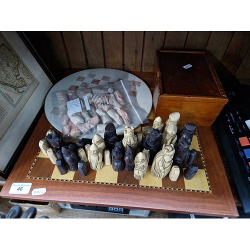 46 - Two chess sets, one soapstone and one wooden, together with another set of pieces.