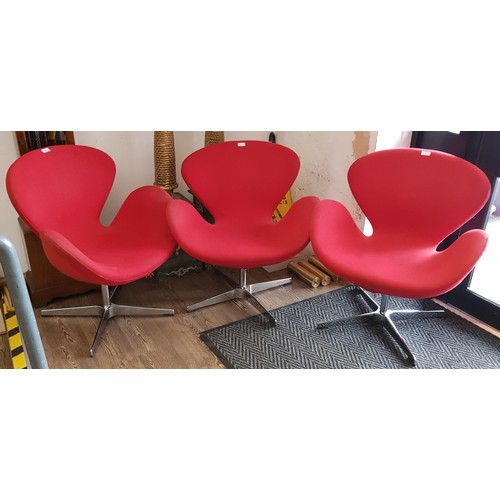 943 - A set of three 'Swan' swivel chairs in red upholstery on chrome bases, designed by Arne Jacobsen.