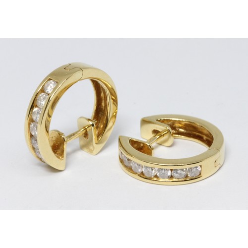 86 - A pair of 18ct gold diamond earrings, of hoop design, each set with seven channel set diamonds, tota... 