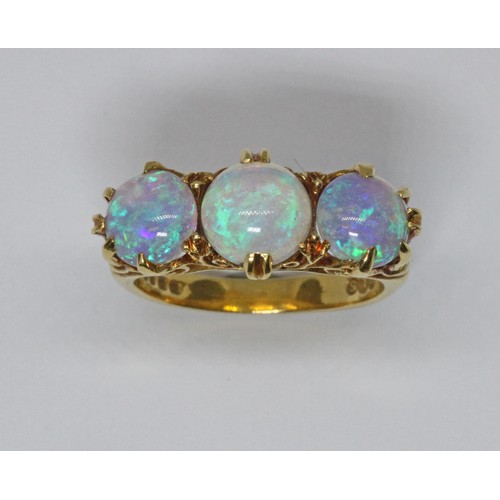 102 - A three stone opal ring, scroll setting with three round opal cabochons, hallmarked 18ct gold, spons... 