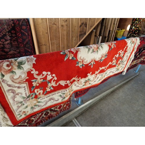 1070 - A Chinese wool carpet, red ground decorated with flowers, 183cm x 122cm approx