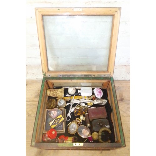 310 - A display case containing assorted collectables, including a bone carving, snuff boxes, chains, port... 