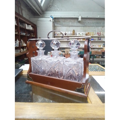 89 - A three bottle mahogany tantalus with cut glass decanters & hallmarked silver labels for whiskey, br... 