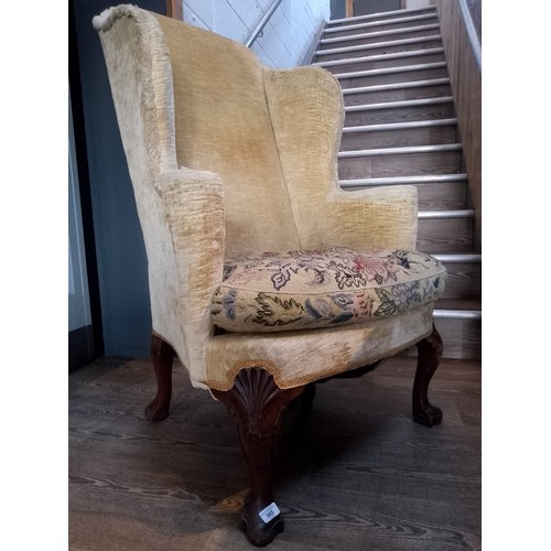 885 - A George I walnut framed wingback armchair with shell carved knees.