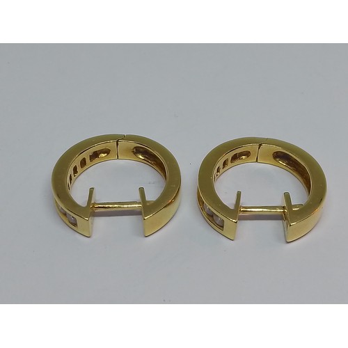 86 - A pair of 18ct gold diamond earrings, of hoop design, each set with seven channel set diamonds, tota... 