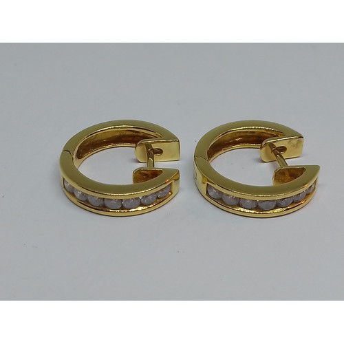 86 - A pair of 18ct gold diamond earrings, of hoop design, each set with seven channel set diamonds, tota... 