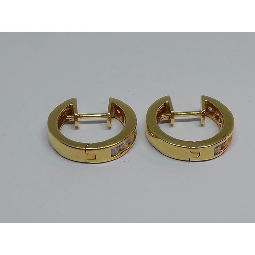 86 - A pair of 18ct gold diamond earrings, of hoop design, each set with seven channel set diamonds, tota... 