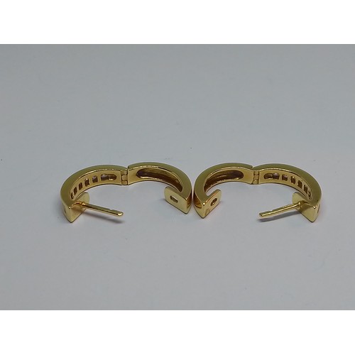 86 - A pair of 18ct gold diamond earrings, of hoop design, each set with seven channel set diamonds, tota... 