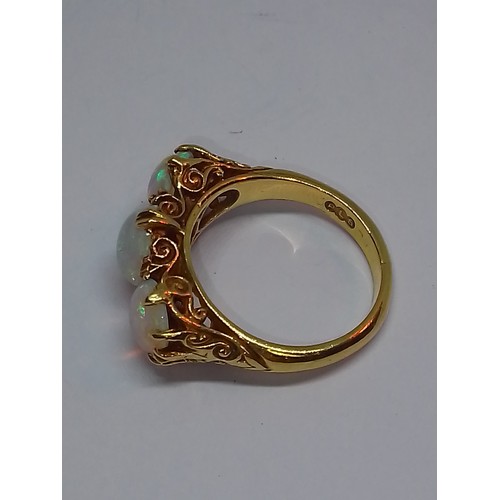 102 - A three stone opal ring, scroll setting with three round opal cabochons, hallmarked 18ct gold, spons... 