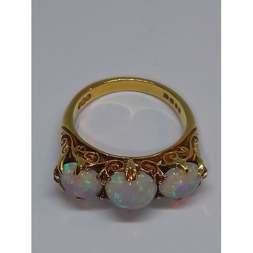 102 - A three stone opal ring, scroll setting with three round opal cabochons, hallmarked 18ct gold, spons... 