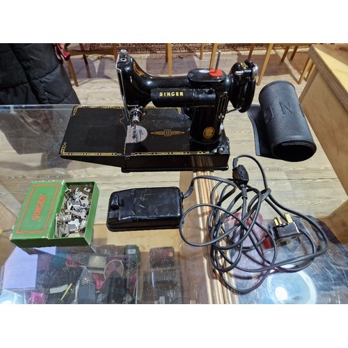 140 - A Singer Featherweight 221K electric travel sewing machine with case and accessories.