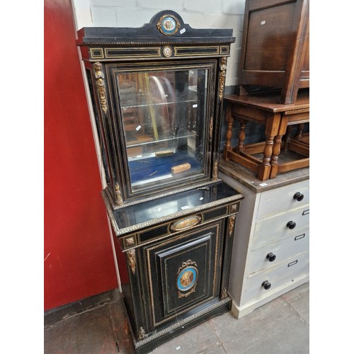 977 - A gilt mounted ebonised cabinet with painted porcelain plaques.