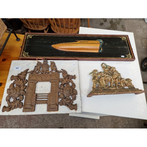 262 - A wooden relief model of a speedboat, a metal ornament and a metal door stop.