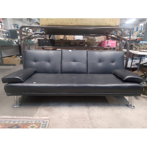 1043 - A chrome and faux leather sofa bed.