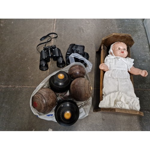 90 - A bag of crown green bowls, 2 pairs of binoculars and an old doll in crib.