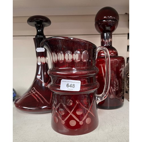 648 - Two cranberry glass decanters, with stoppers, and a similar water jug