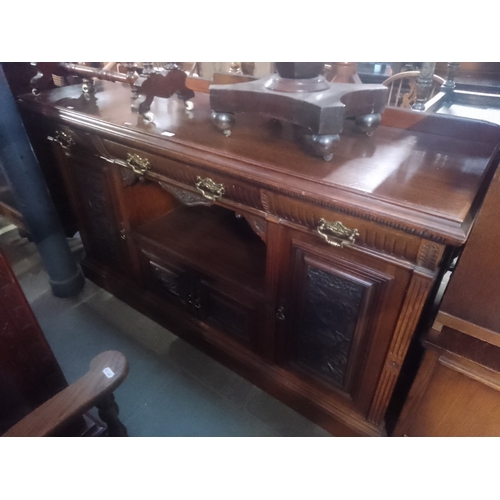 932 - An Edwardian oak sideboard with carved panels.