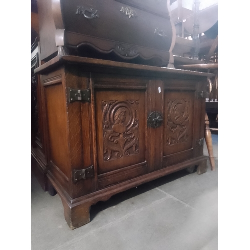 934 - An aged oak cabinet with carved panels to the doors.