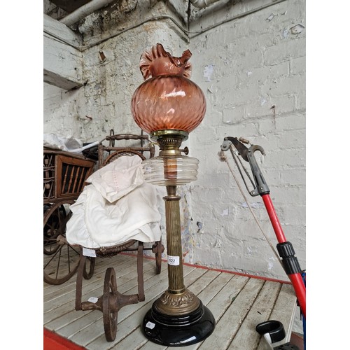 122 - A brass and glass paraffin lamp with cranberry glass shade.