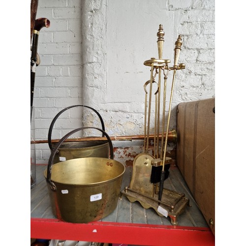 129 - Two large brass jam pans together with two copper and brass coaching horns and brass fire tidy.