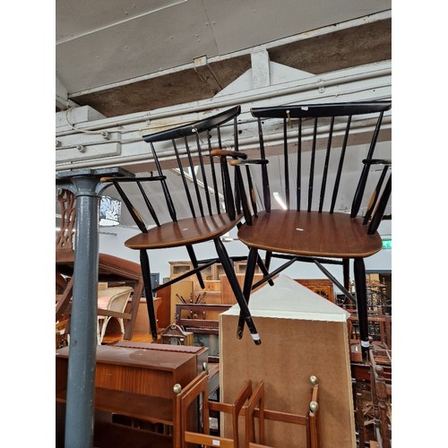 944 - A pair of mid 20th century teak and black spindle back armchairs/carvers.