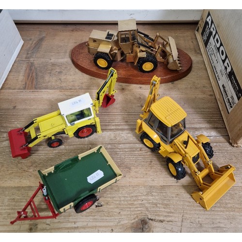 336 - Four model JCB diggers/trailer comprising one presentation model on plinth, one by NZG, another by D... 