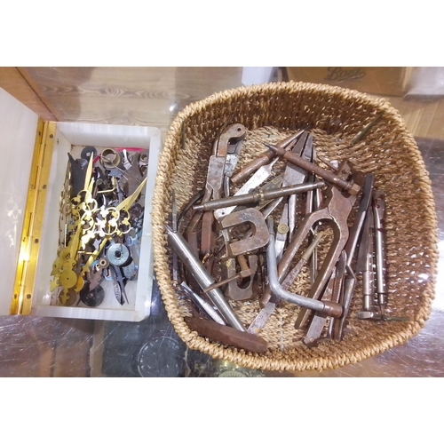 310 - A box of grandfather clock hands and a basket of assorted horology tools.