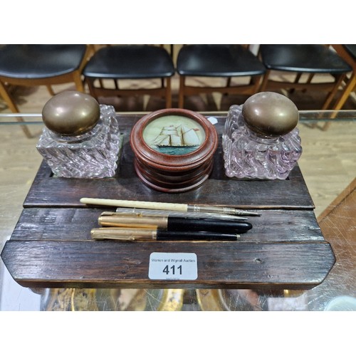 411 - An oak desk stand with glass inkwells together with Parker pens, propelling pencils and a wooden pot... 