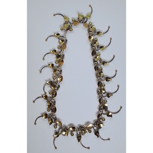 22 - Brett Payne - an 18ct gold and silver necklace, cast silver links with flowers (some) marked '750', ... 