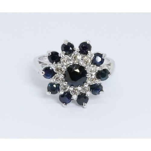 124 - A diamond and sapphire cluster ring, the cluster measuring approximately 16mm in diameter, white met... 