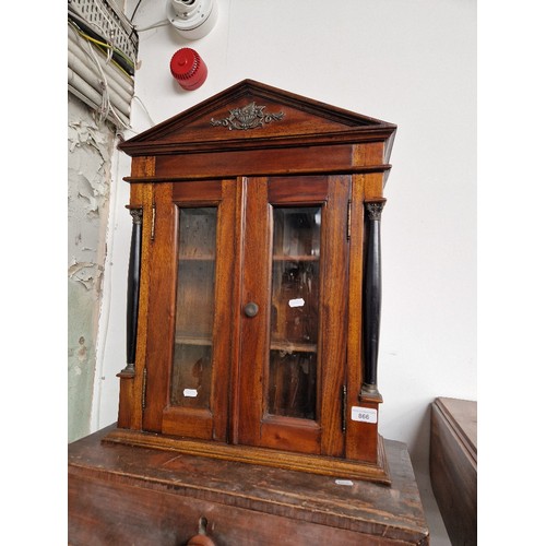 866 - A glazed mahogany wall cabinet with bevelled glass and flanked by ebonised columns.