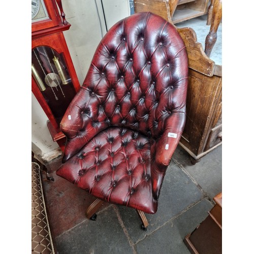 885 - An oxblood red leather Chesterfield swivel chair.