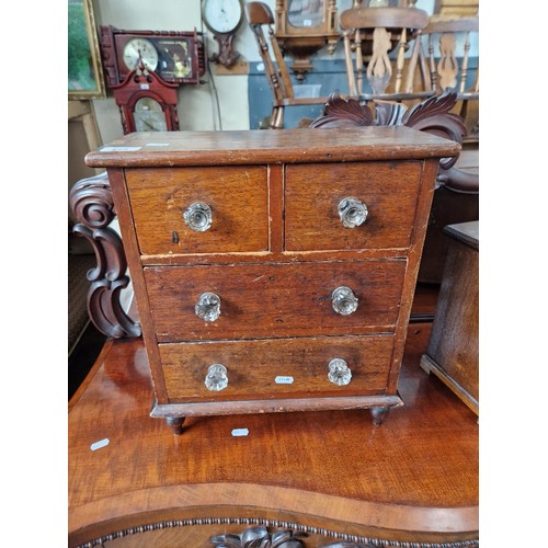 890 - A Victorian mahogany miniature chest of drawers with pressed glass handles.