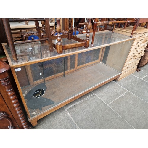 893 - A vintage glass shop display cabinet, length 179cm.