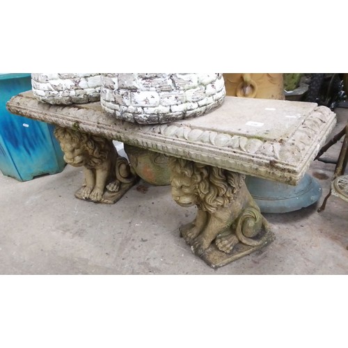 236 - A concrete garden bench on lion plinths