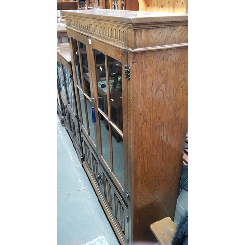 958 - A glazed oak bookcase with linenfold panels to the doors.