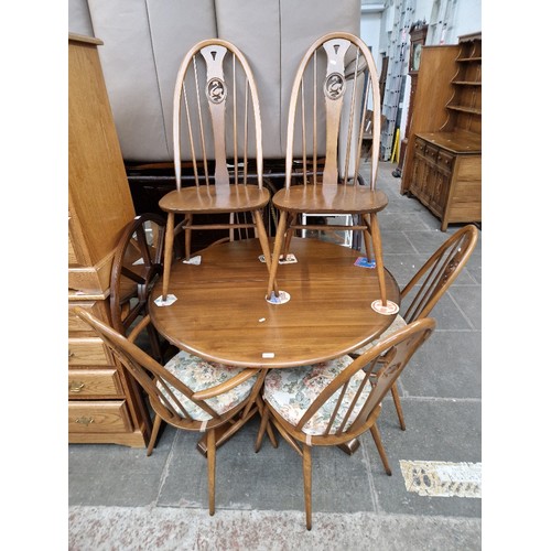 993 - An Ercol elm extending dining table and six swan back chairs, including two carvers.