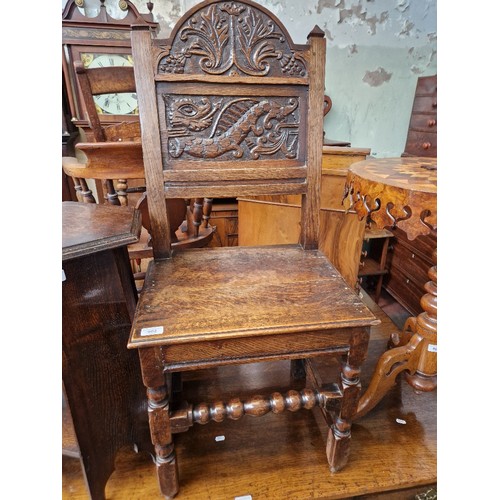 902 - An 18th century carved oak chair with dragon to the back.