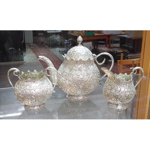 419 - An Egyptian three piece silver tea set, profusely decorated with flowers, cobra snake handles, essay... 