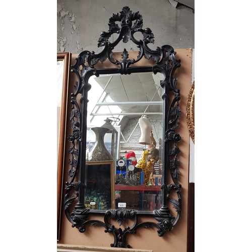 815 - A French style wall mirror, ebonised carved wood frame, 124cm x 59cm (overall).