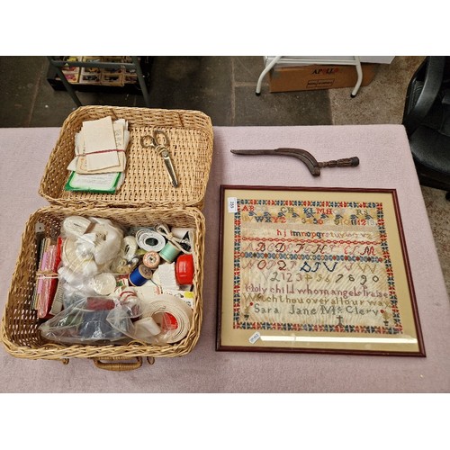 255 - A carved wood knitting sheath together with a basket of haberdashery and a needlework sampler dated ... 