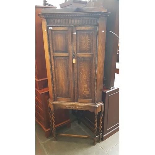 936 - A 1920s oak corner cabinet on twist supports.