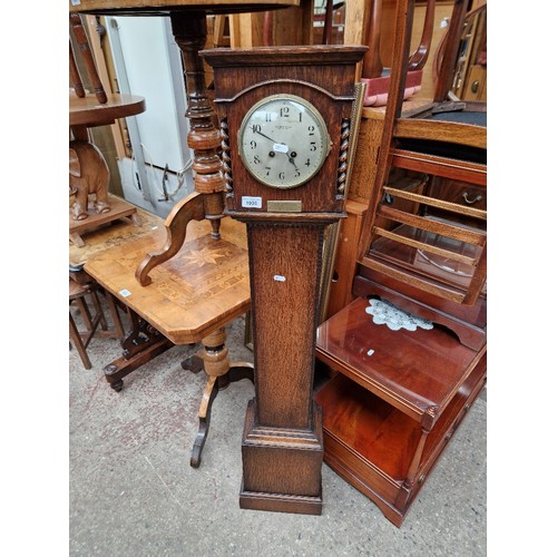 1026 - A 1920s oak cased granddaughter clock by Waring and Gillow with presentation plaque for 1925.