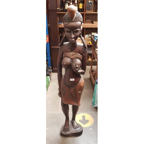 116 - An African carved hardwood figures modelled as a woman and child, height 130cm.