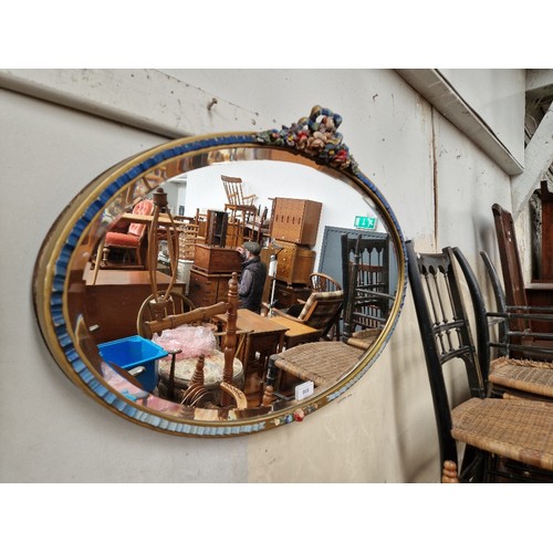 908 - A 1930s Barbola oval wall mirror, decorated with flowers, 71cm x 47.5cm.