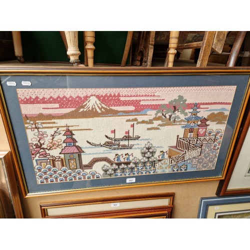 902 - A framed needlework picture, Japanese scene depicting Mount Fuji with boats and figures to foregroun... 