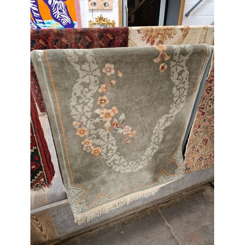 953 - A Chinese wool carpet, green ground decorated with flowers, 90cm x 205cm (approx).