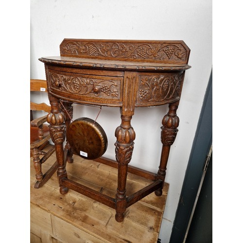 967 - A 1920s/1930s carved oak demi lune side table with gong.