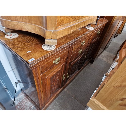 1006 - An Edwardian oak sideboard with carved panels to the doors, length 152cm.