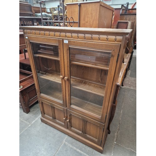 1025 - An Ercol elm bookcase, bevelled glass to the doors.